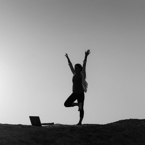 Person feeling energized and stretching towards the sky at sunrise.