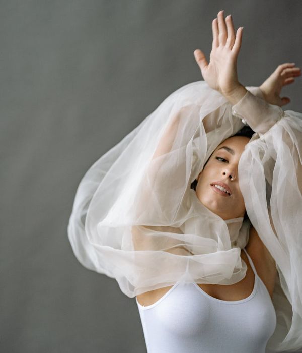 Woman performing a calm, flowing movement in a minimalist studio.